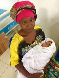 A mother holding her baby on a blanquet is prepared to leave the hospital and going back home.